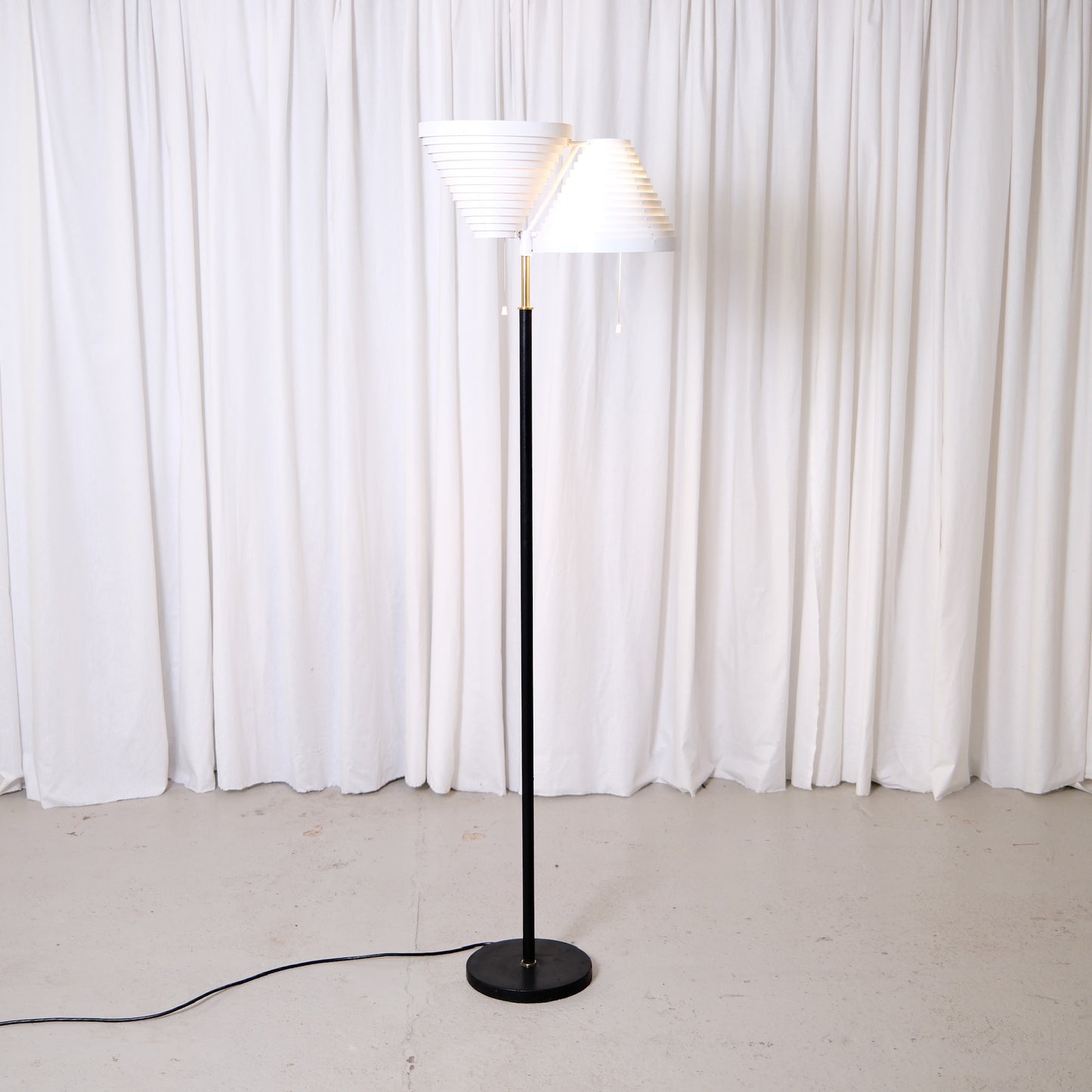 Rare Alvar Aalto A809 floor lamp manufactured by Valaisinpaja. Collectible Finnish modern lighting design with layered white metal shades and brass details.
