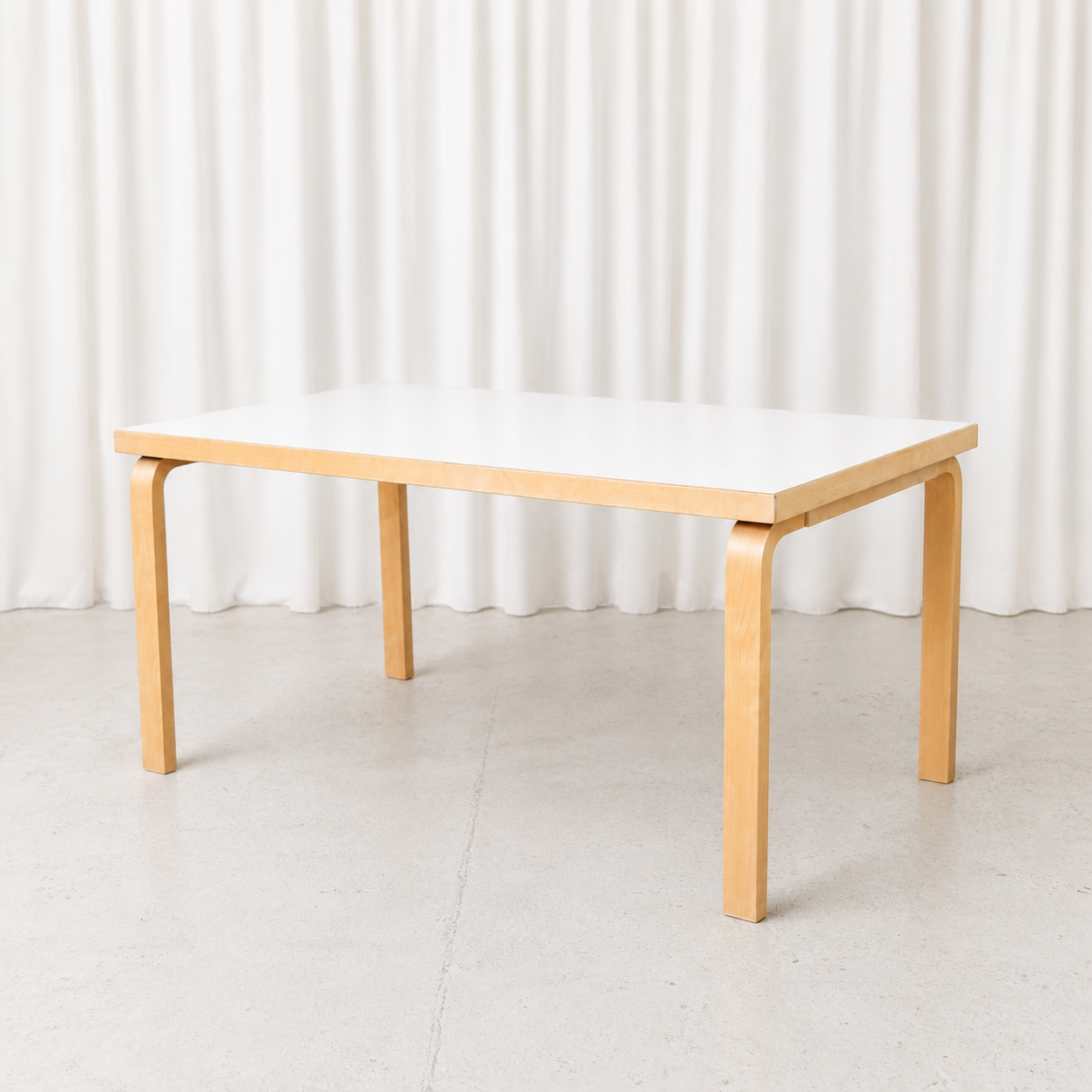 Vintage Artek 82A table designed by Alvar Aalto, featuring a white laminate top and bent birch legs. Very good condition. Measures 150 × 85 × 74 cm.