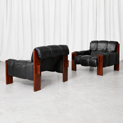 A pair of vintage Brazilian armchairs with black leather upholstery and wooden frames. A bold and comfortable lounge pair with a strong Brazilian modernist character.