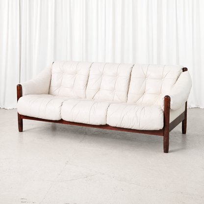Vintage Brazilian style three-seater sofa with a stained beech frame and button-tufted white leather cushions. A sculptural and comfortable vintage piece.