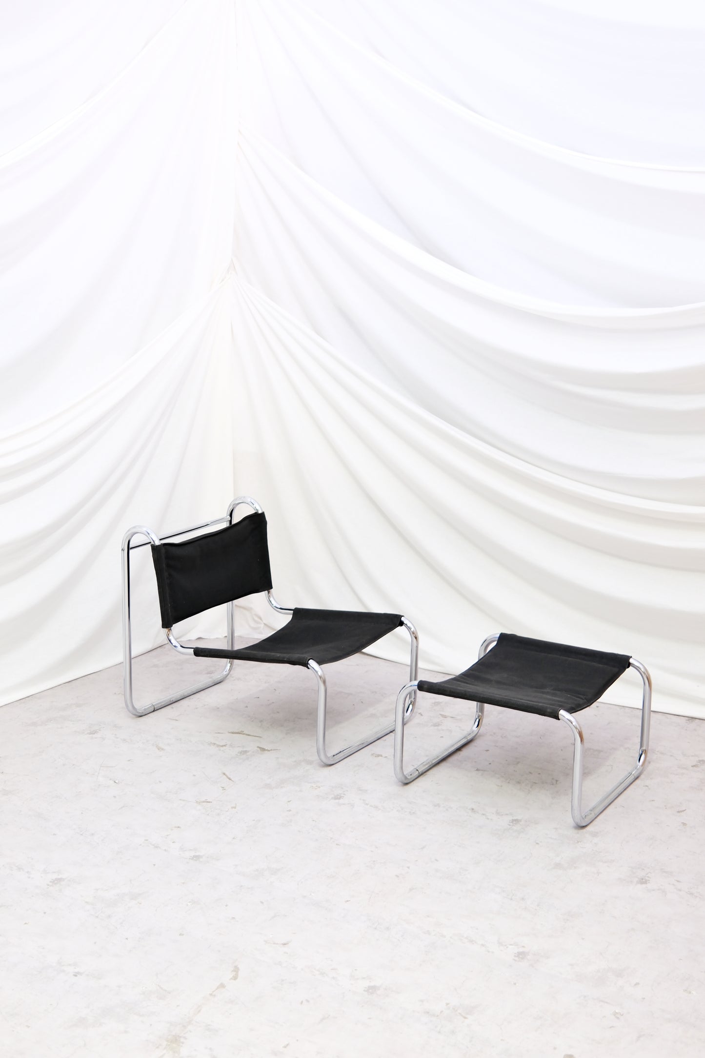 Vintage chrome lounge chair with matching ottoman. Tubular steel frame and black sling upholstery. Timeless modernist design. Worldwide shipping available.