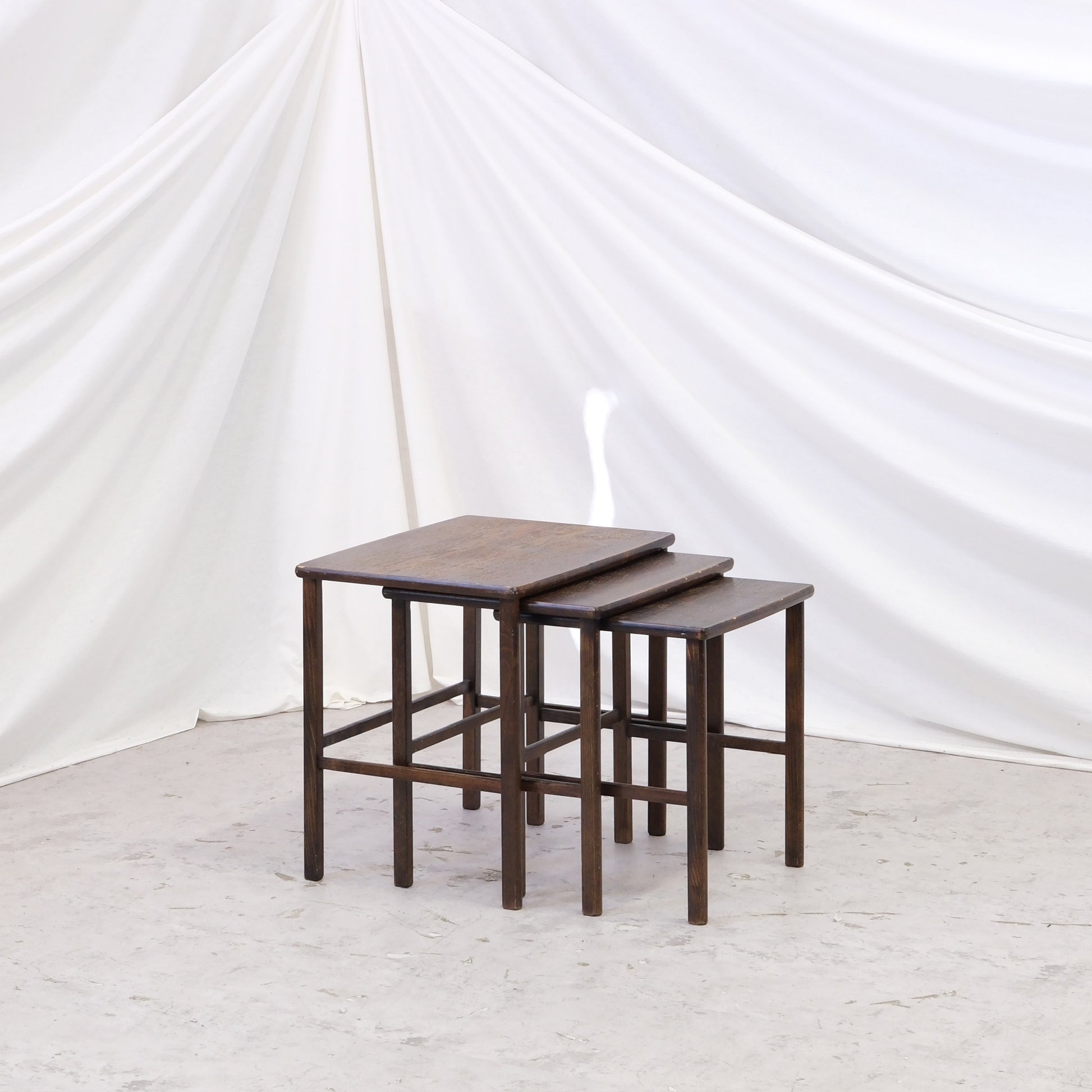 Vintage dark wood nesting tables with a warm patinated finish. A practical three-piece side table set with timeless character. Worldwide shipping available.