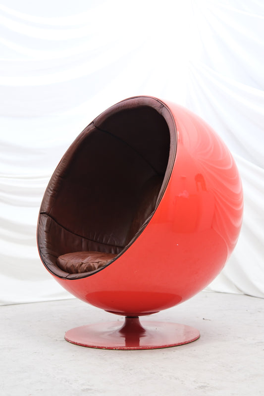 Original vintage Eero Aarnio Ball Chair with red fiberglass shell and brown leather interior. Iconic Finnish design from Helsinki. Worldwide shipping available.
