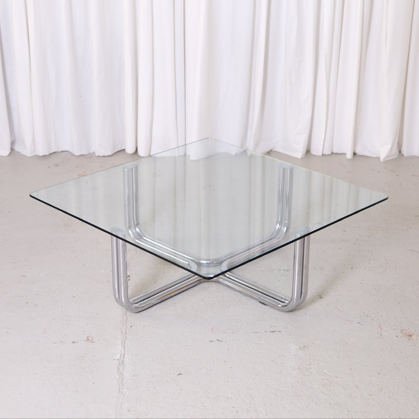 Vintage Italian glass coffee table with square 110 x 110 cm top and chrome tubular steel base. Good vintage condition with minor glass wear.