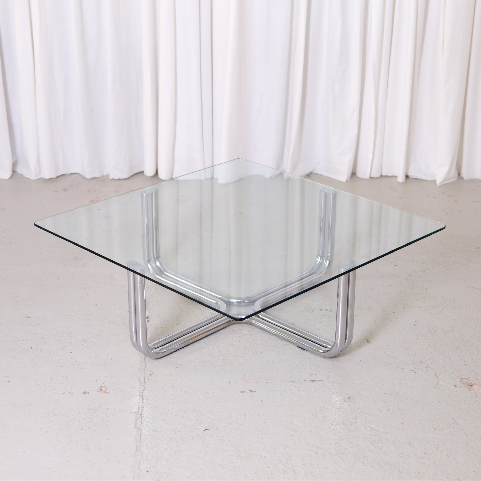 Vintage Italian glass coffee table with square 110 x 110 cm top and chrome tubular steel base. Good vintage condition with minor glass wear.