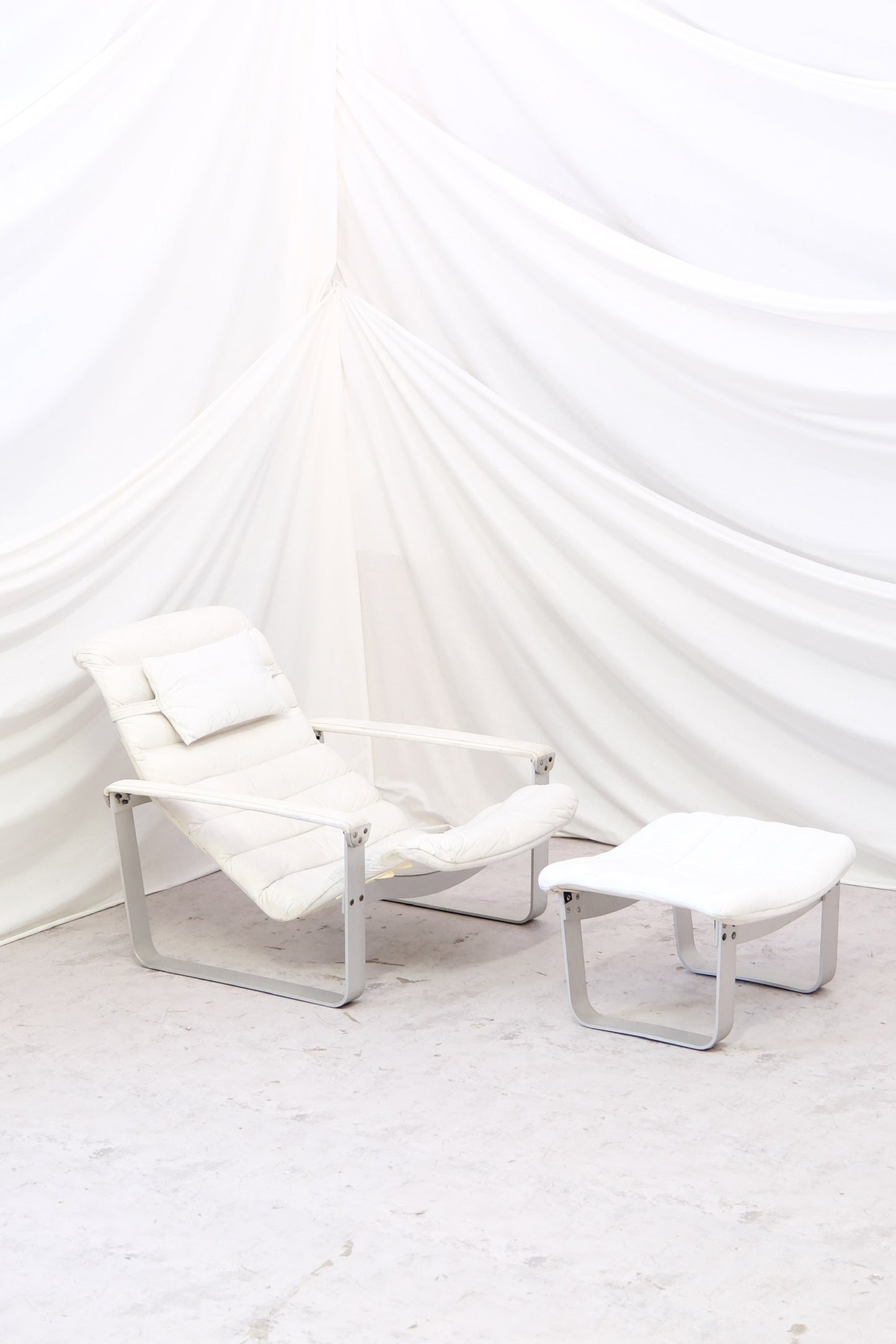 1970s Ilmari Lappalainen Pulkka chair with ottoman for Asko. White leather, visible wear, original Finnish design. Worldwide shipping available.