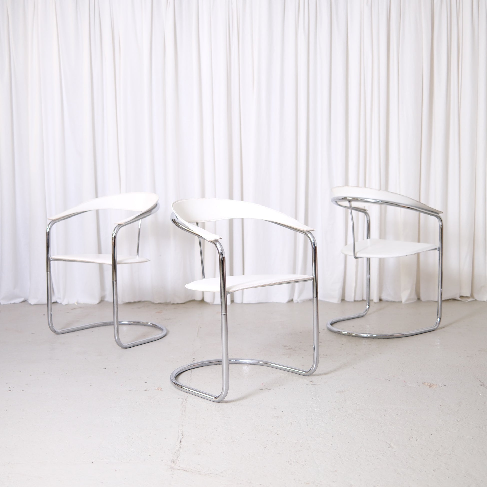 Vintage Italian chrome and white leather dining chairs with curved armrests and open metal frames