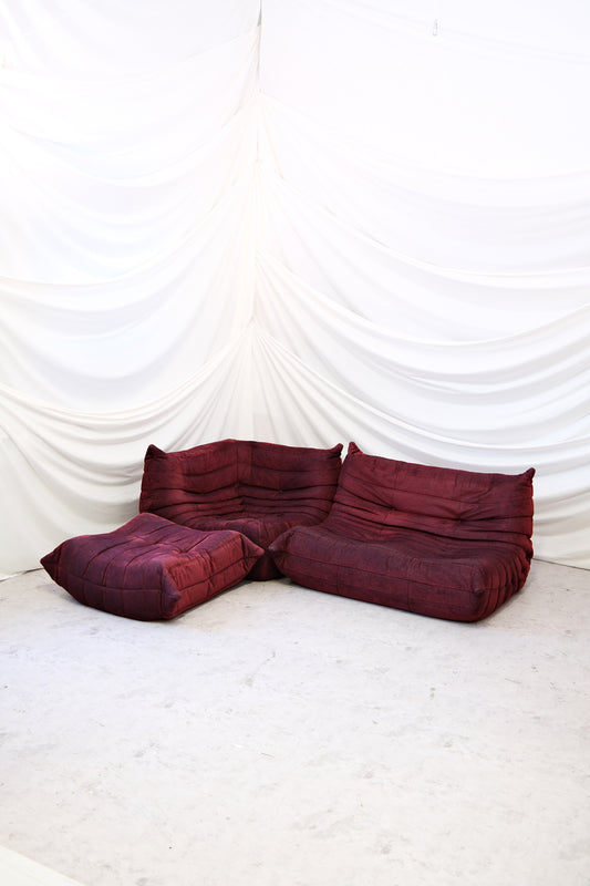 Original Ligne Roset Togo set in burgundy fabric with two seater, corner module and ottoman. Designed by Michel Ducaroy. Available with worldwide shipping from Helsinki.