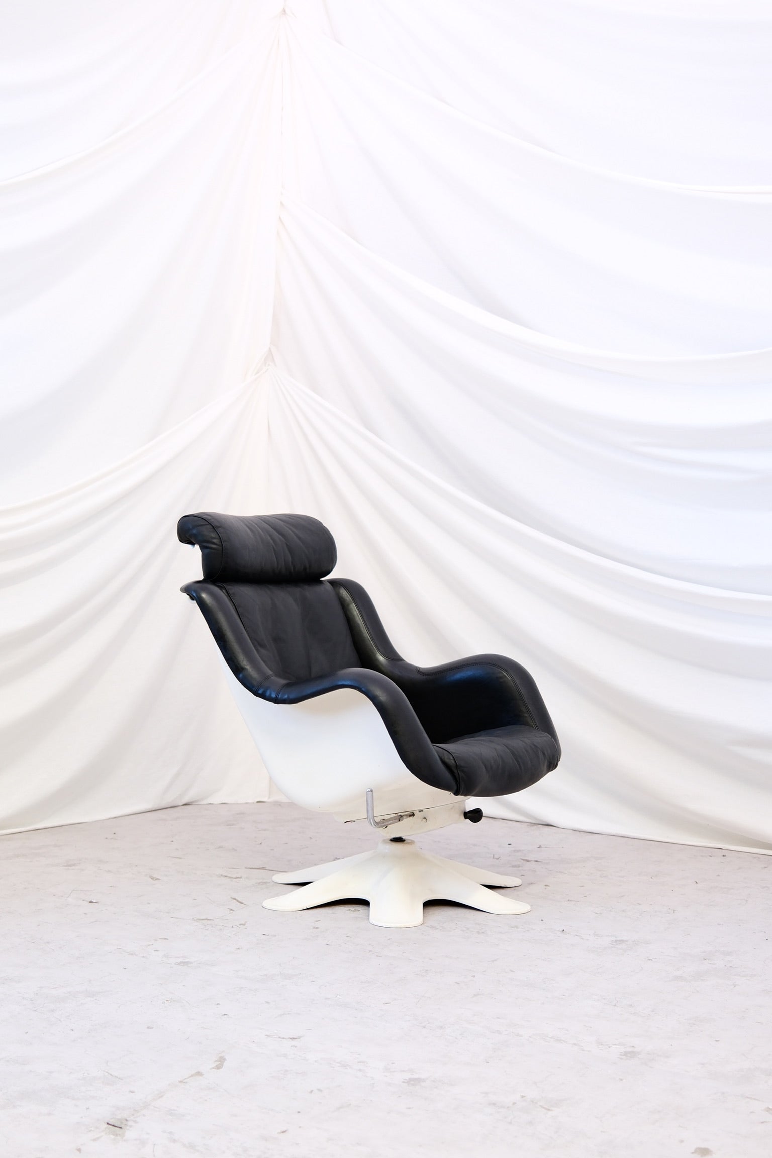 Finnish design classic by Yrjö Kukkapuro for Haimi. Model 418 in black leather with white shell, three recline positions and removable headrest. Worldwide shipping.