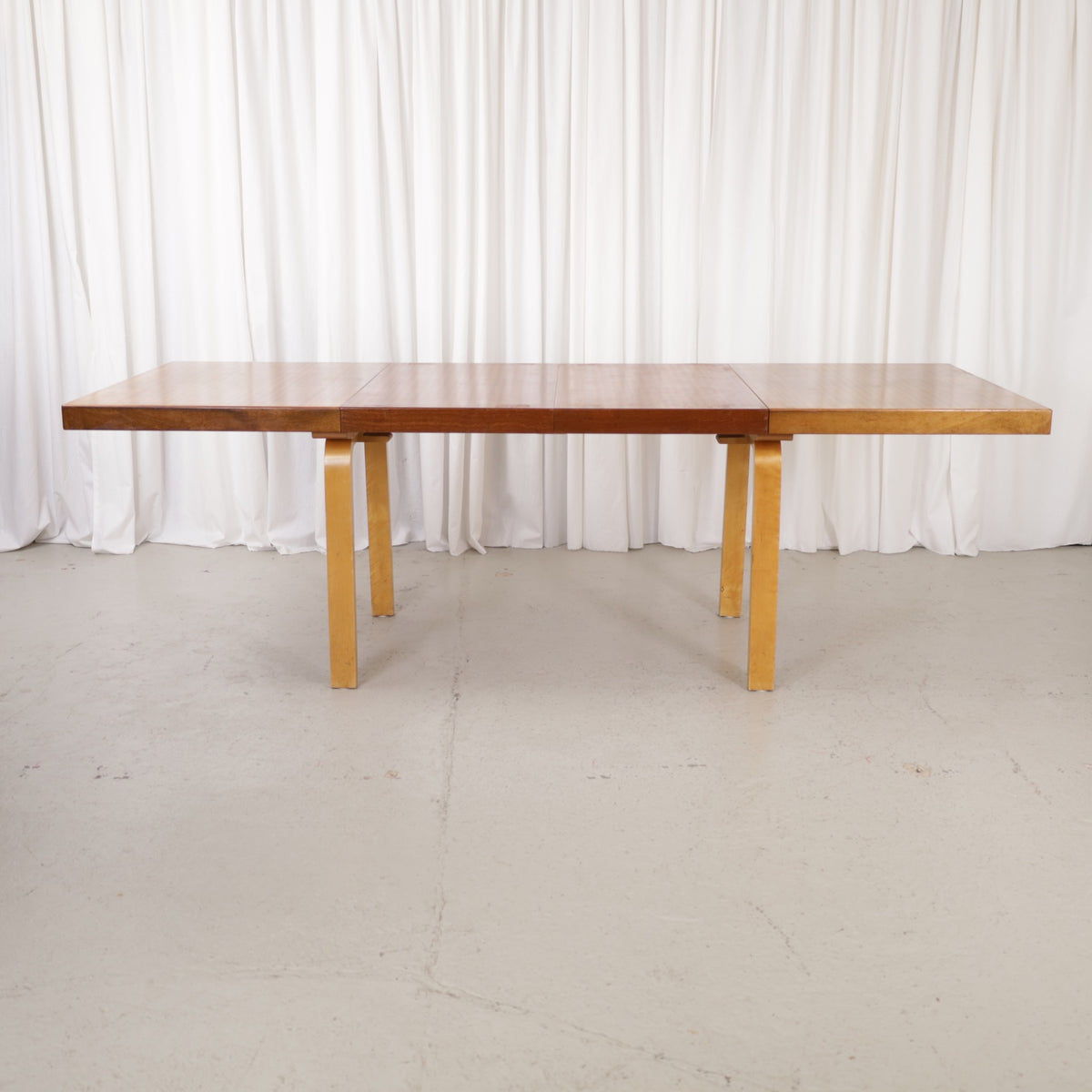 Alvar Aalto extendable teak table with figured birch legs — full table view