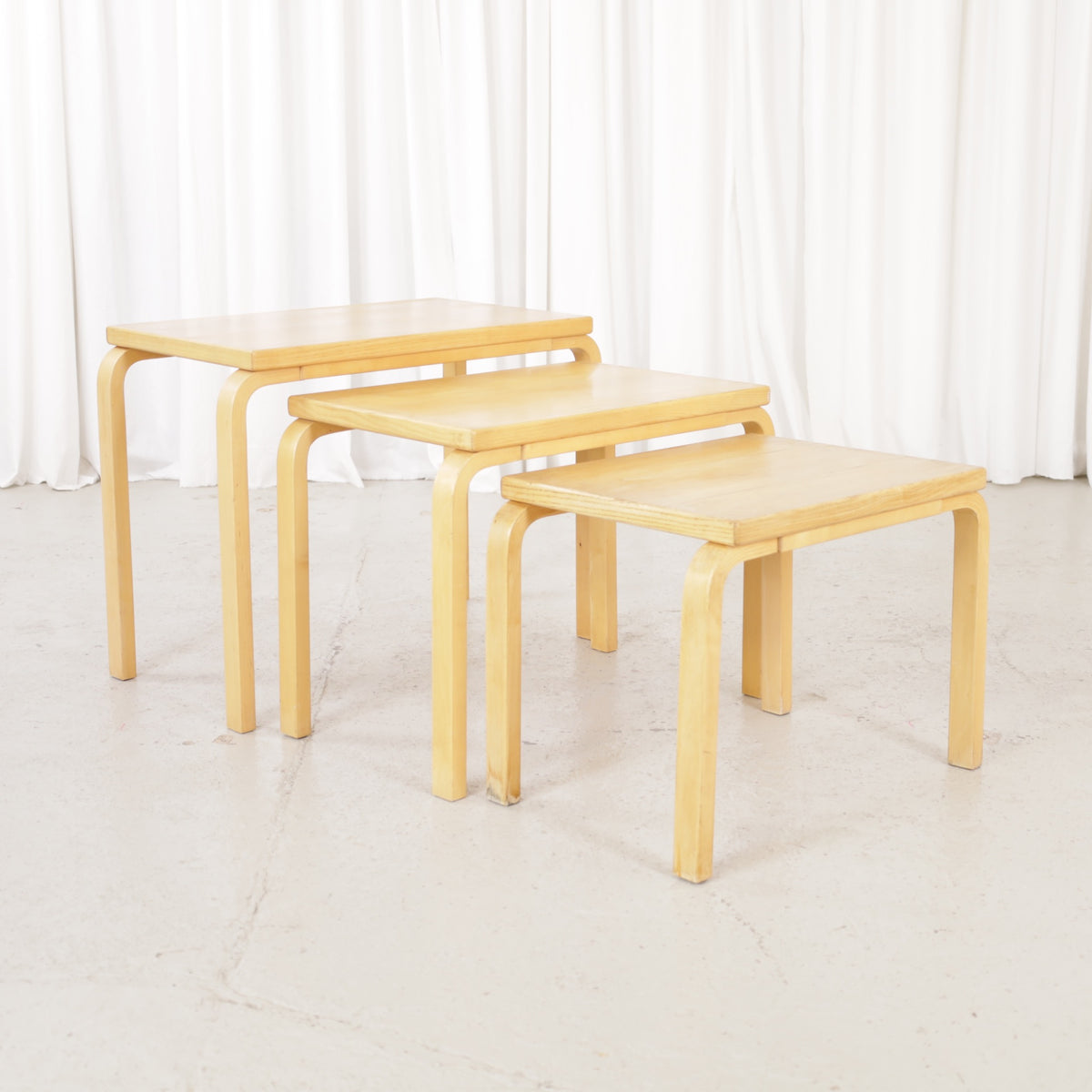 Alvar Aalto nesting tables for Artek, patinated wooden surfaces and bent legs