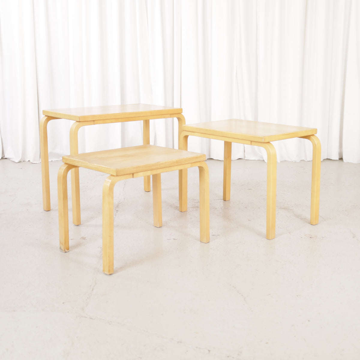 Alvar Aalto nesting tables for Artek, patinated wooden surfaces and bent legs