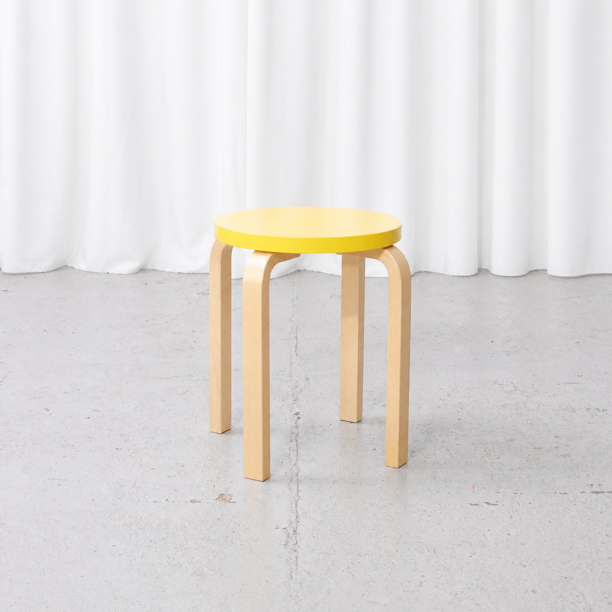 Alvar Aalto E60 stool for Artek with a yellow lacquered seat, front view