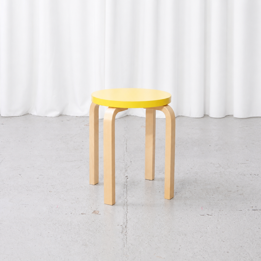 Alvar Aalto E60 stool for Artek with a yellow lacquered seat, front view