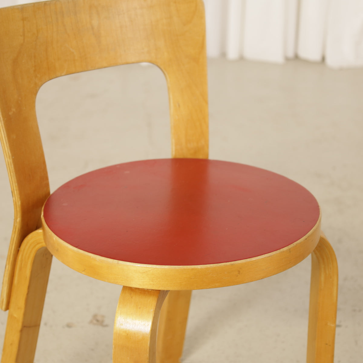Alvar Aalto Chair 65 in Birch and Red Linoleum for Artek, close-up of red linoleum seat and birch backrest on Chair 65