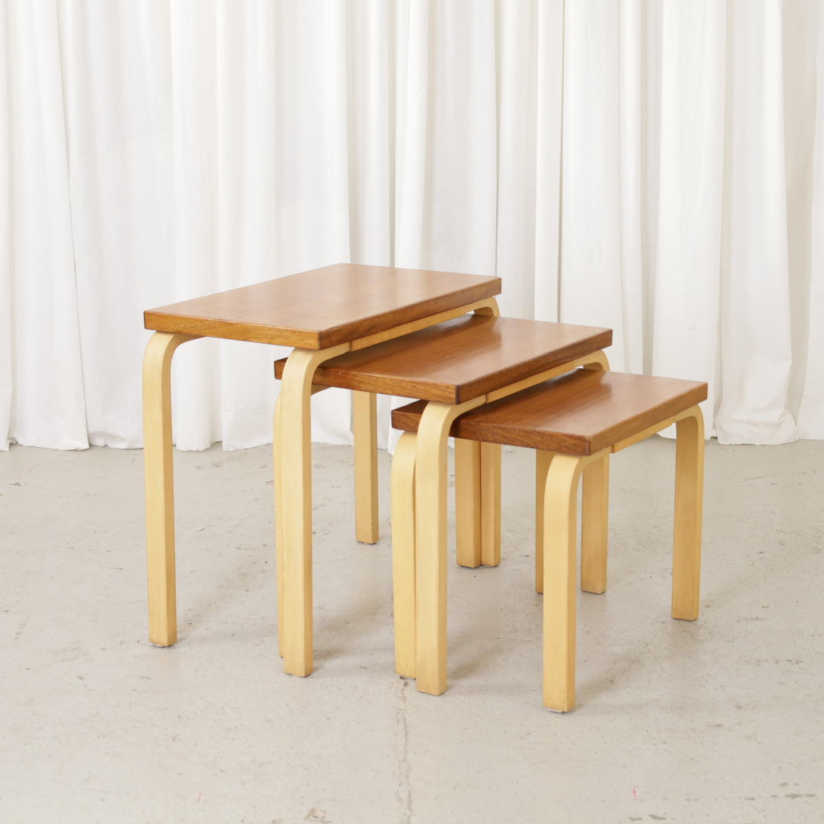 Alvar Aalto Nesting Table Set in Mahogany and Birch, 1950s, three wooden nesting tables arranged in a stepped row