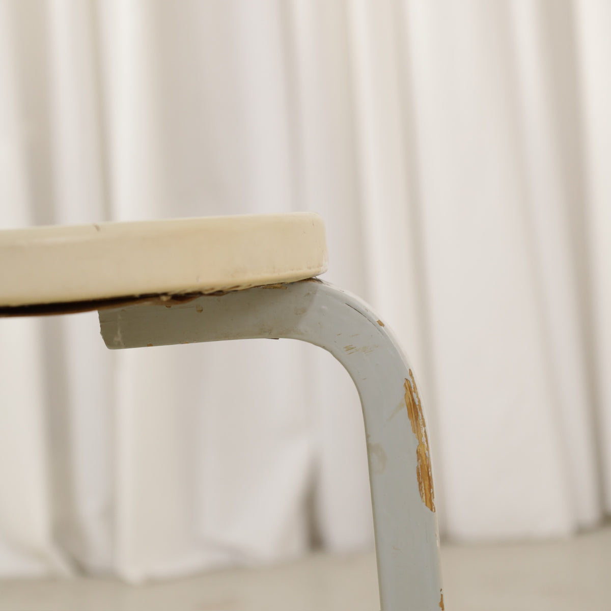 Alvar Aalto Stool 60 for Artek with Light Upholstered Seat, close-up of paint wear on a leg and wear beneath the seat