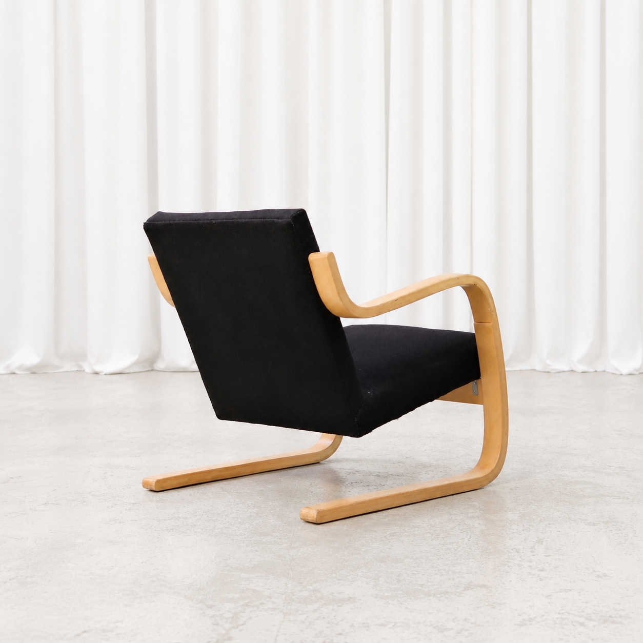 Rear side view of an Artek 402 armchair showing its bent birch frame