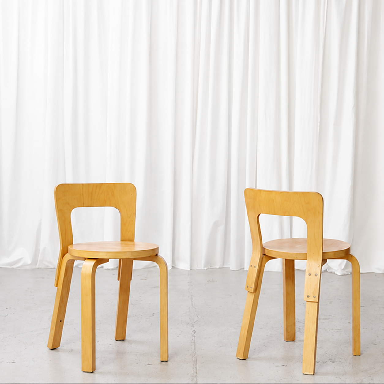 Front and rear views of vintage Artek 65 birch chairs with finger-jointed legs