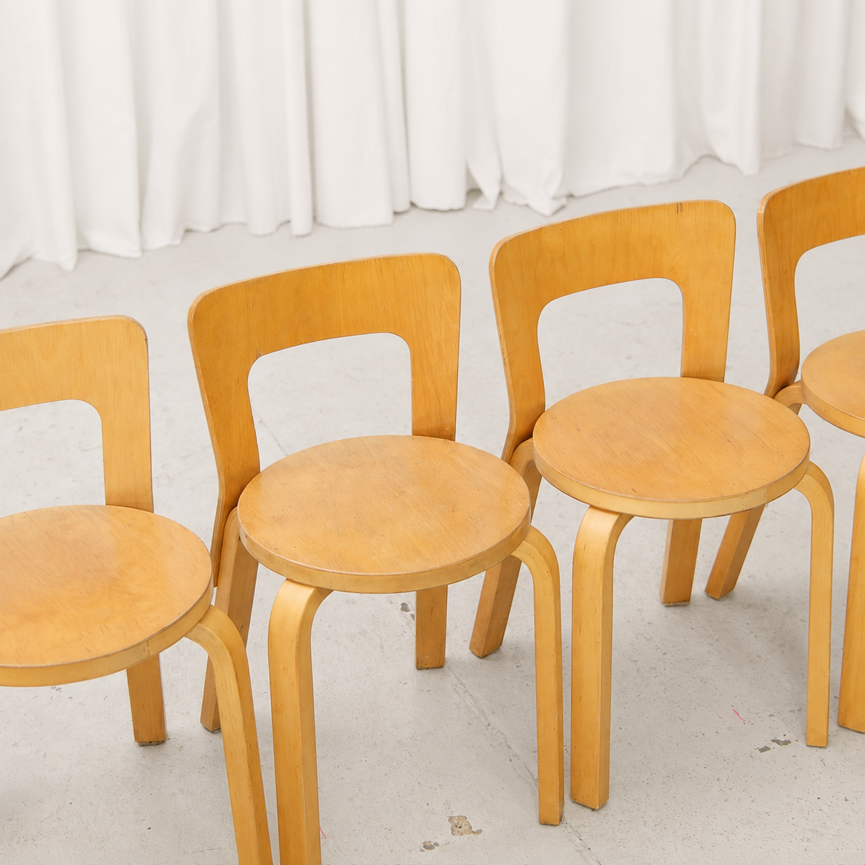 Detail of four vintage Artek 65 birch chairs showing honey-toned patina and surface wear