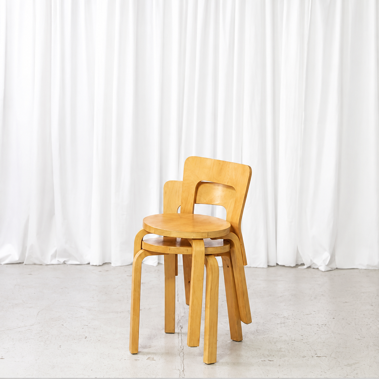 Two stackable vintage Artek 65 birch chairs with honey-toned patina