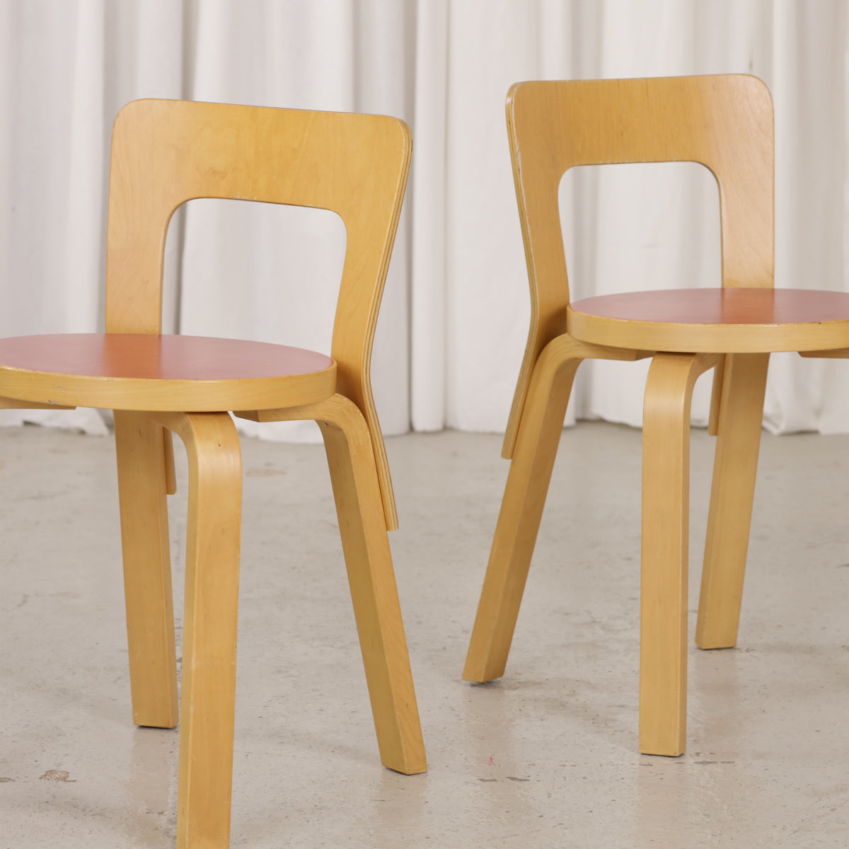 Detail of two Artek Chair 65 chairs with red linoleum seats