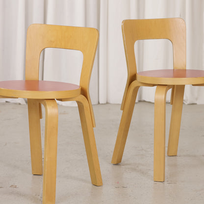 Detail of two Artek Chair 65 chairs with red linoleum seats