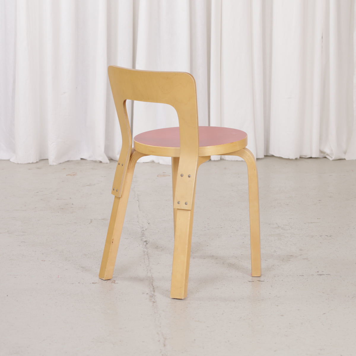 Artek Chair 65 with red linoleum seat, rear three-quarter view