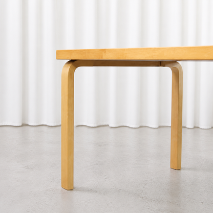 Close view of the curved birch L-leg and white laminate tabletop