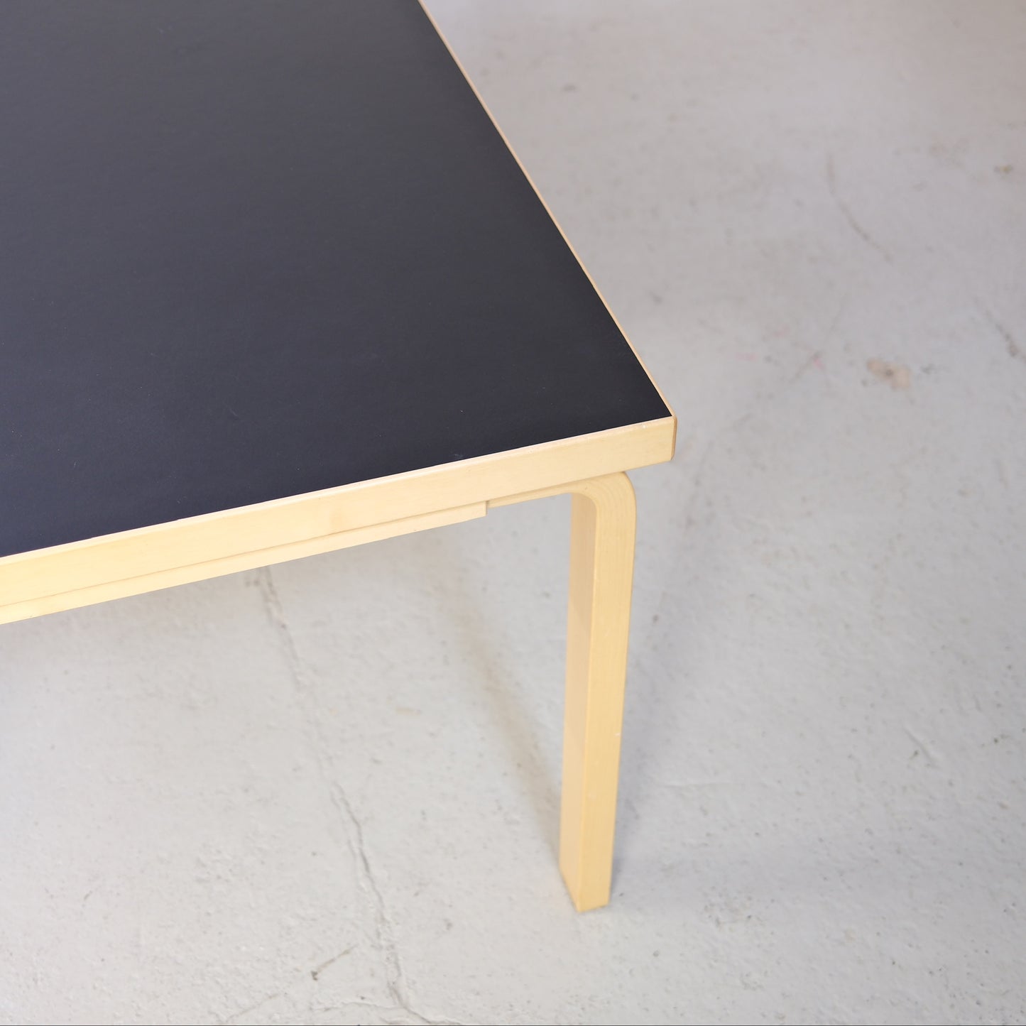 Corner detail of the black linoleum top and birch frame of Artek Table 83