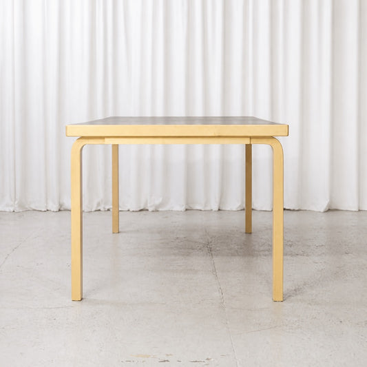 Front view of Artek Table 83 with birch L-legs and black top