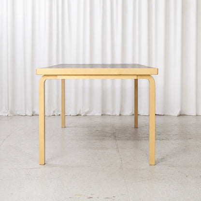 Front view of Artek Table 83 with birch L-legs and black top