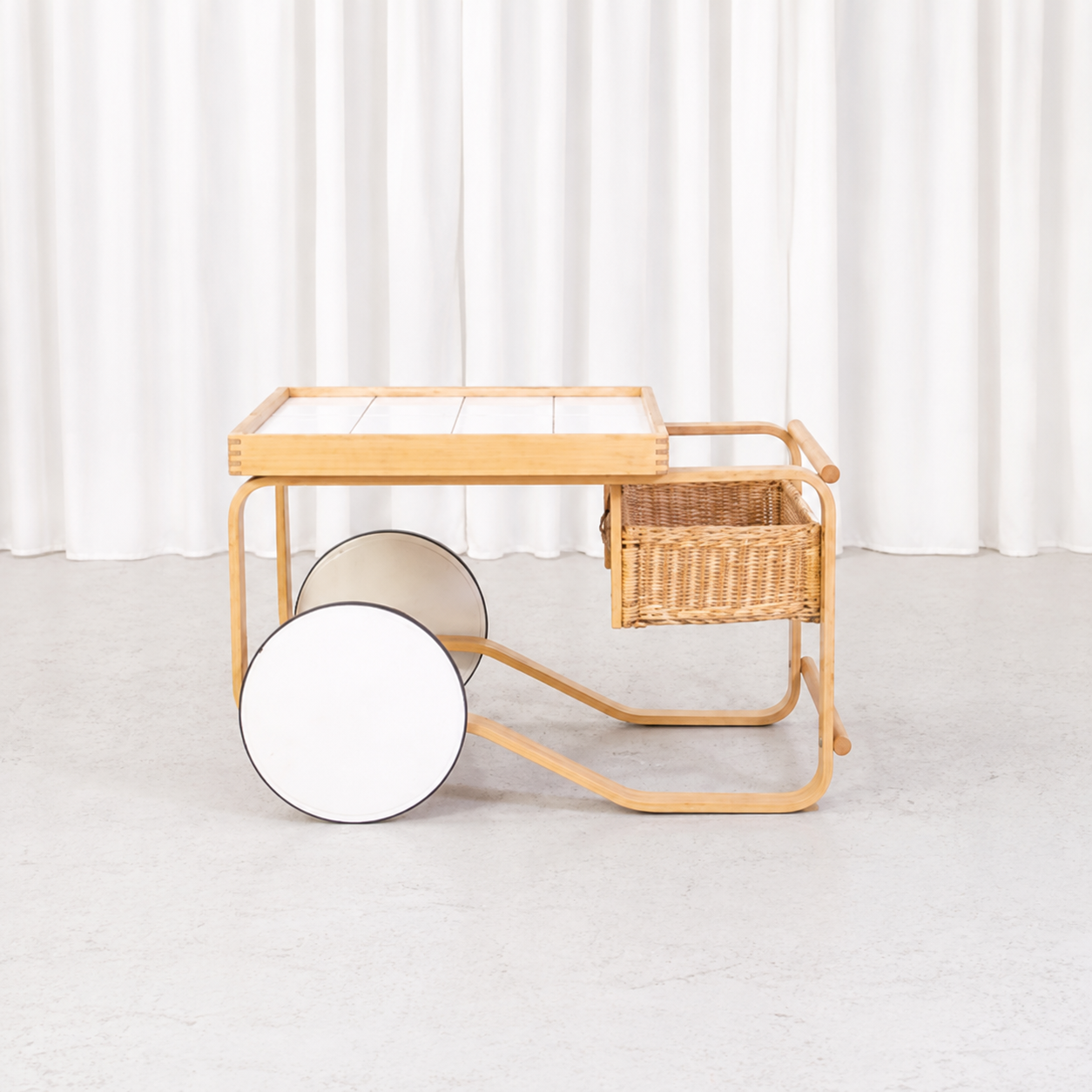 Profile view of Artek Tea Trolley 900 and woven rattan basket