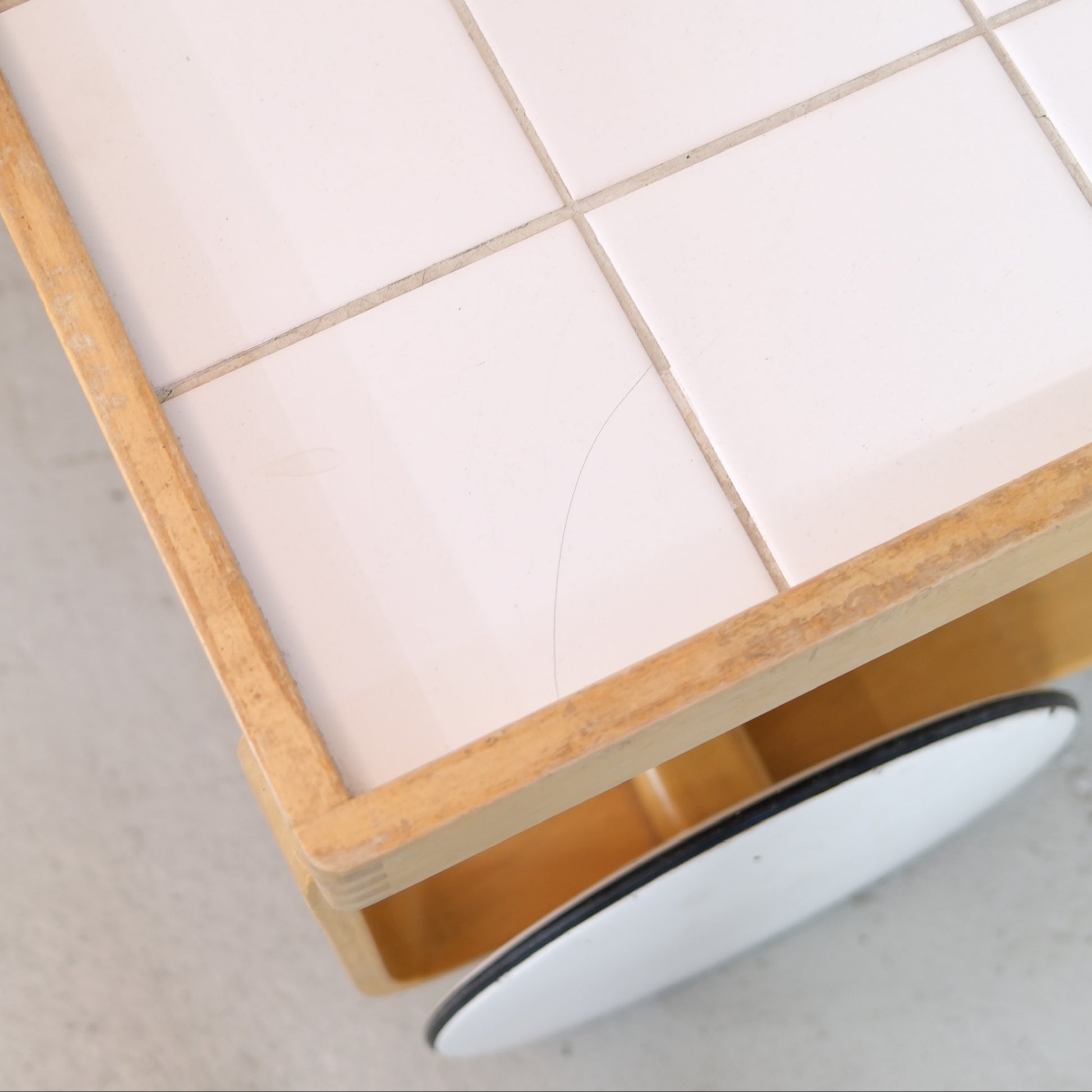Hairline scratch and wear on the white ceramic tiled top