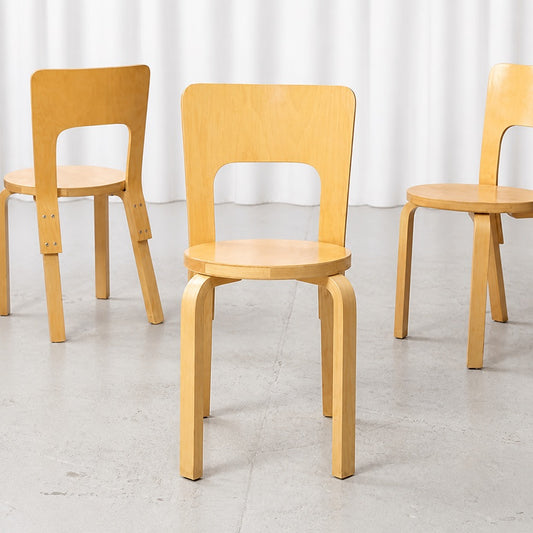 Front view of an Artek Chair 66 in birch with two matching chairs behind