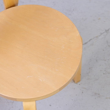 Close-up of scratches and surface wear on the birch seat of an Artek Chair 66