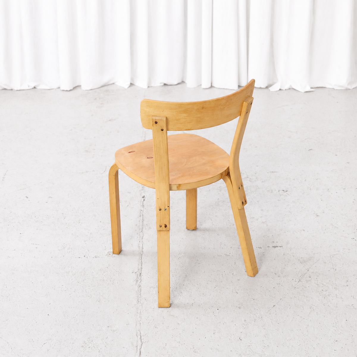 Rear angled view showing finger-jointed legs of an Artek Chair 69