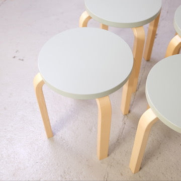 Close view of an Artek E60 stool with a mint-green seat
