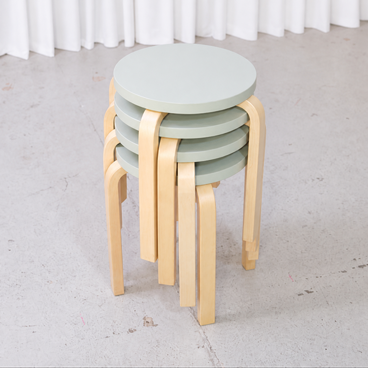 Top view of four stacked Artek E60 stools with mint-green seats