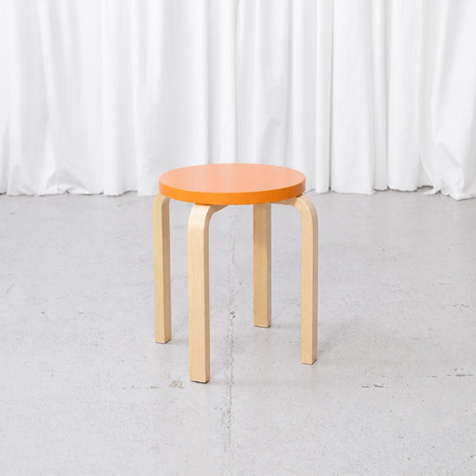 Artek E60 stool with an orange lacquered birch seat and natural birch legs