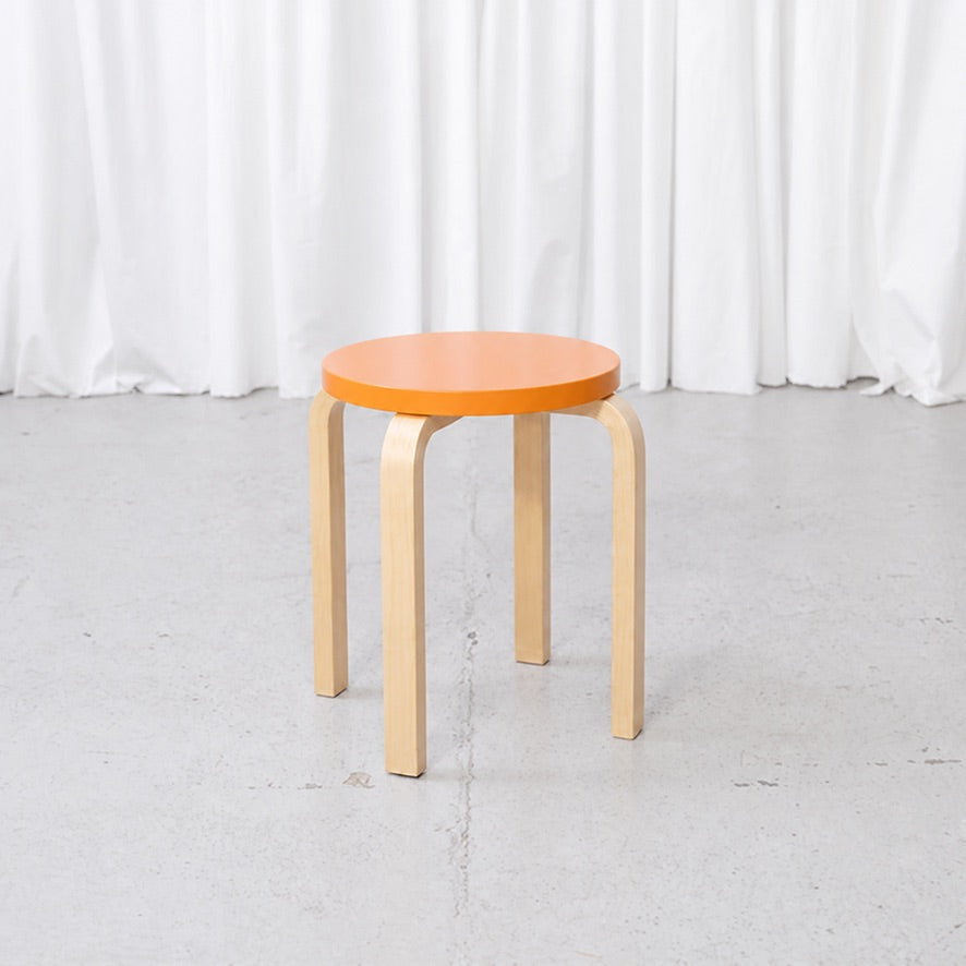 Artek E60 stool with an orange lacquered birch seat and natural birch legs
