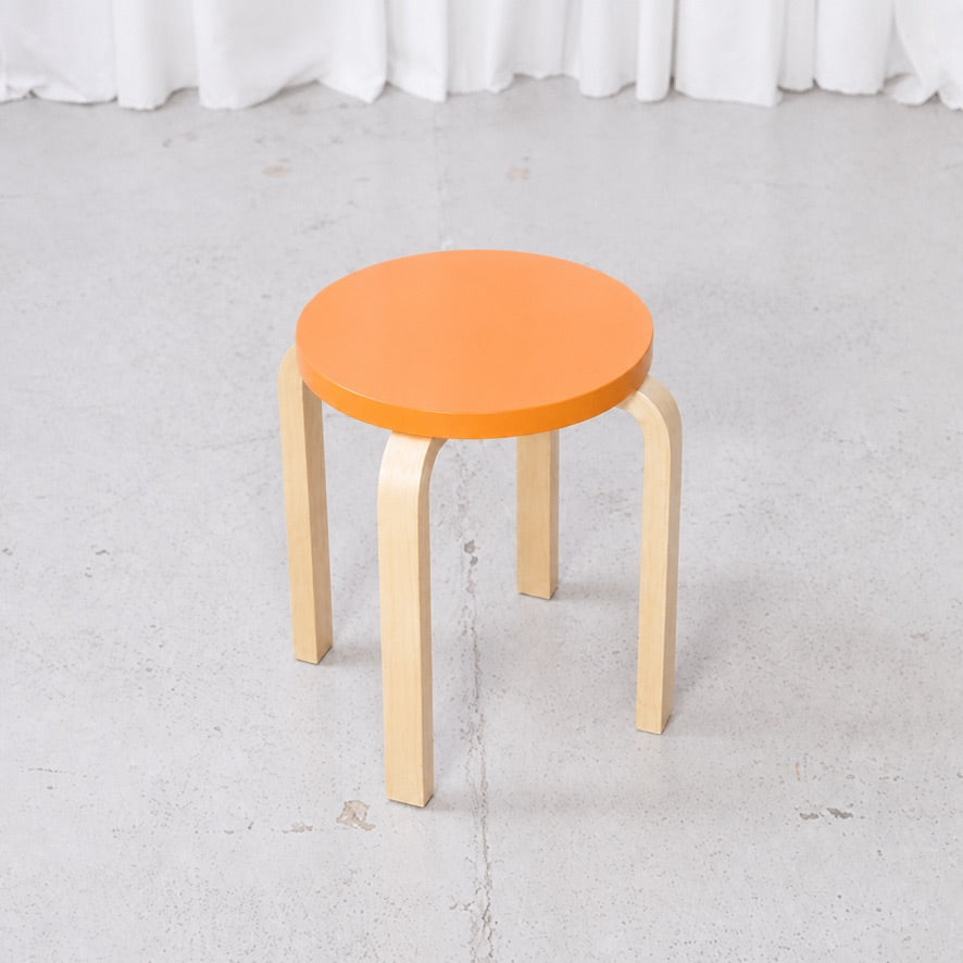 Artek E60 stool viewed from above with an orange lacquered birch seat