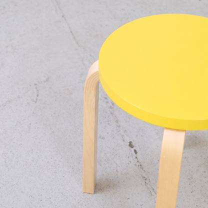 Detail of the yellow lacquered seat and bent birch L-leg on an Artek E60 stool