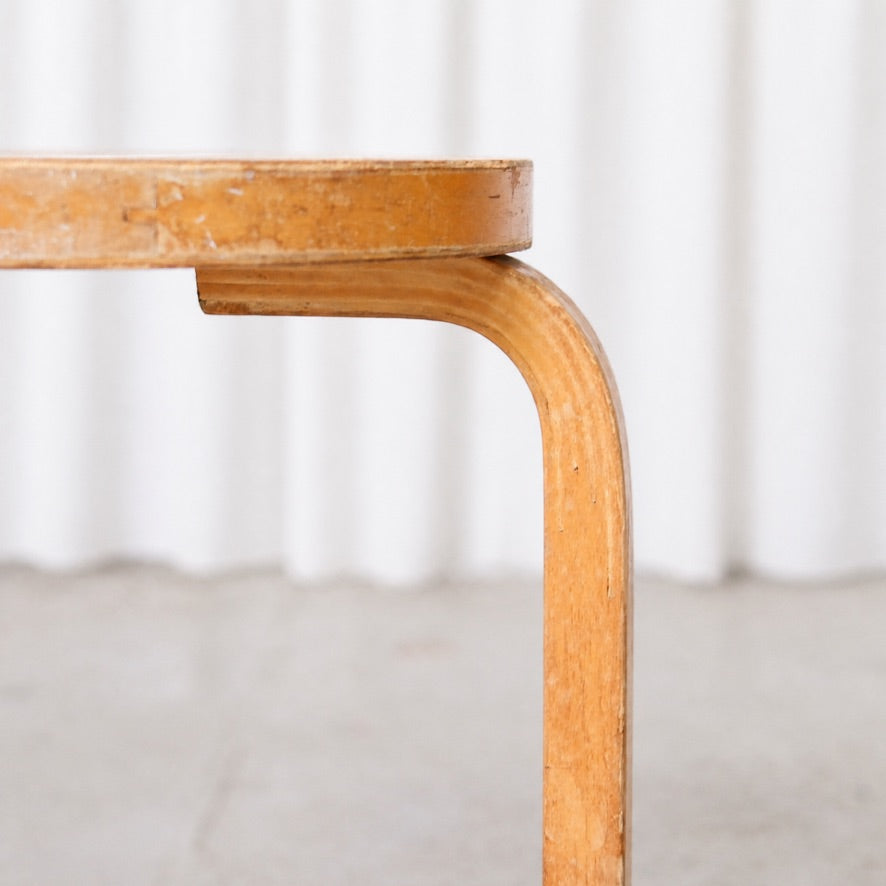 Detail of the curved birch L-leg and seat edge on Artek Stool 60