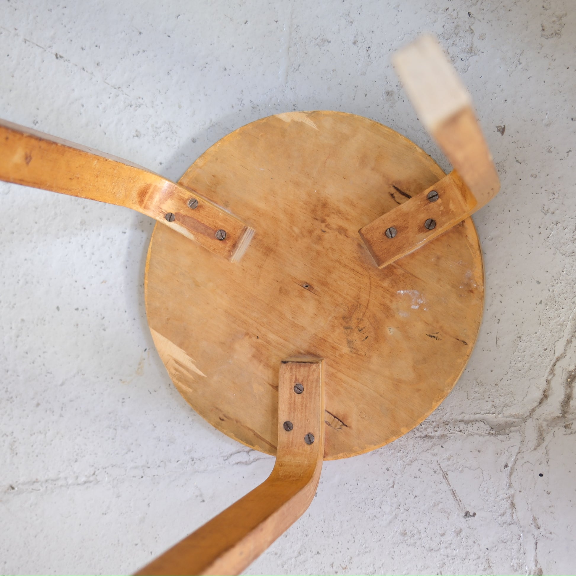 Underside of Artek Stool 60 showing three birch legs and screw fixings