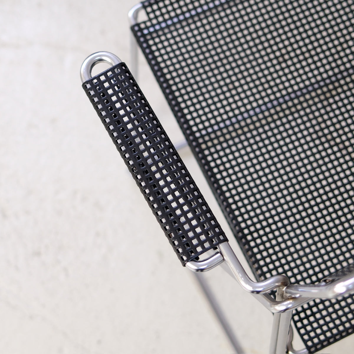 Detail of the black perforated steel armrest and seat on a Hybodan X-Line chair
