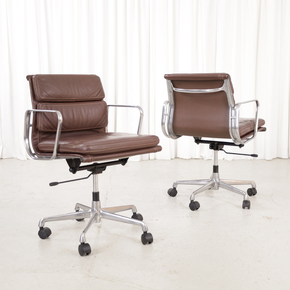 Two brown leather ICF Soft Pad office chairs with castors