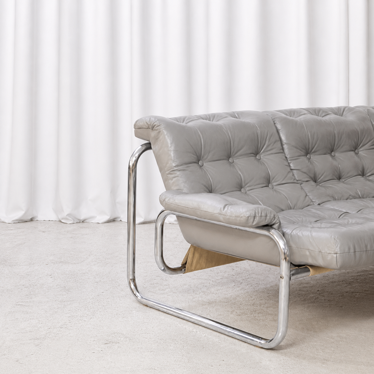 Side detail of grey leather upholstery and chrome frame on IKEA Borkum sofa