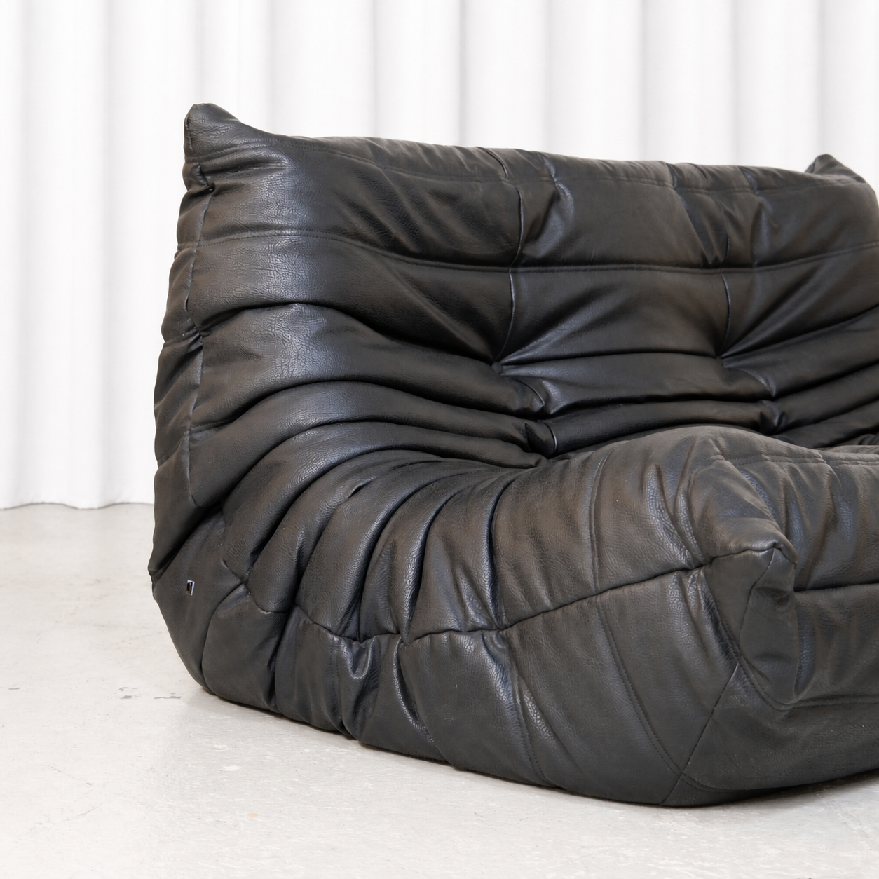 Close view of the quilted black synthetic leather upholstery on the Ligne Roset Togo sofa.