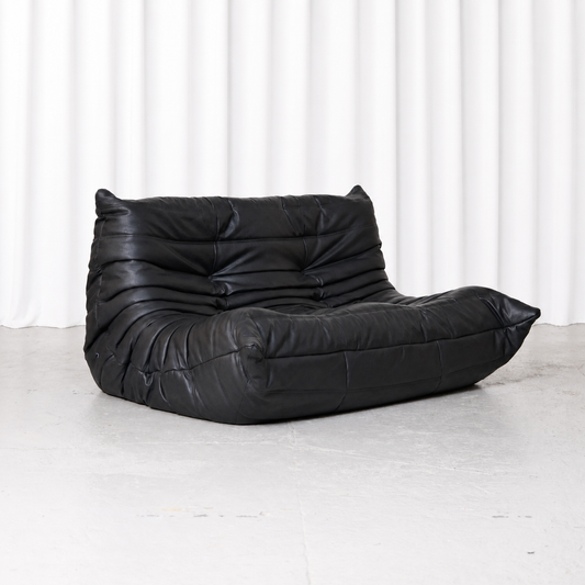 Black synthetic leather Ligne Roset Togo two-seater sofa designed by Michel Ducaroy, front three-quarter view.